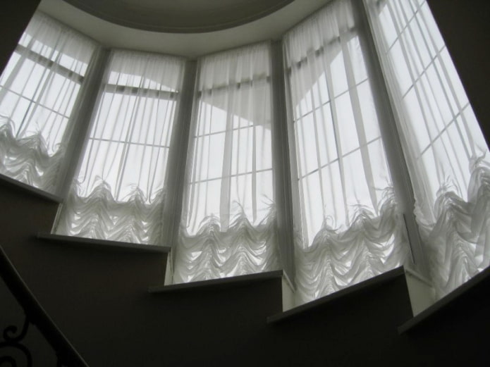 Cortinas austriacas en las ventanas a lo largo de las escaleras