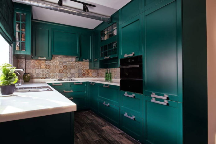 cocina esmeralda oscura con faldón de mosaico