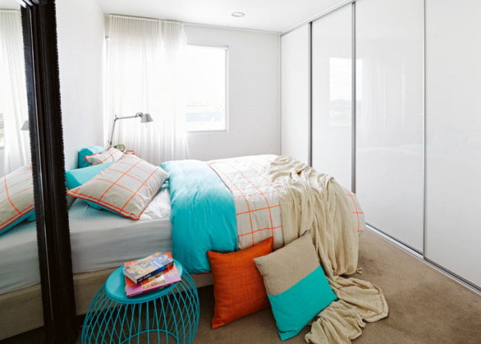 Cama frente a un armario con puertas brillantes