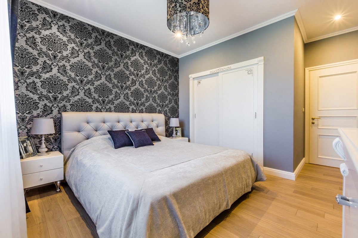 Papel pintado gris con un monograma oscuro en el dormitorio
