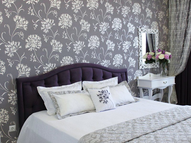 Motivos florales blancos sobre papel pintado gris en el dormitorio