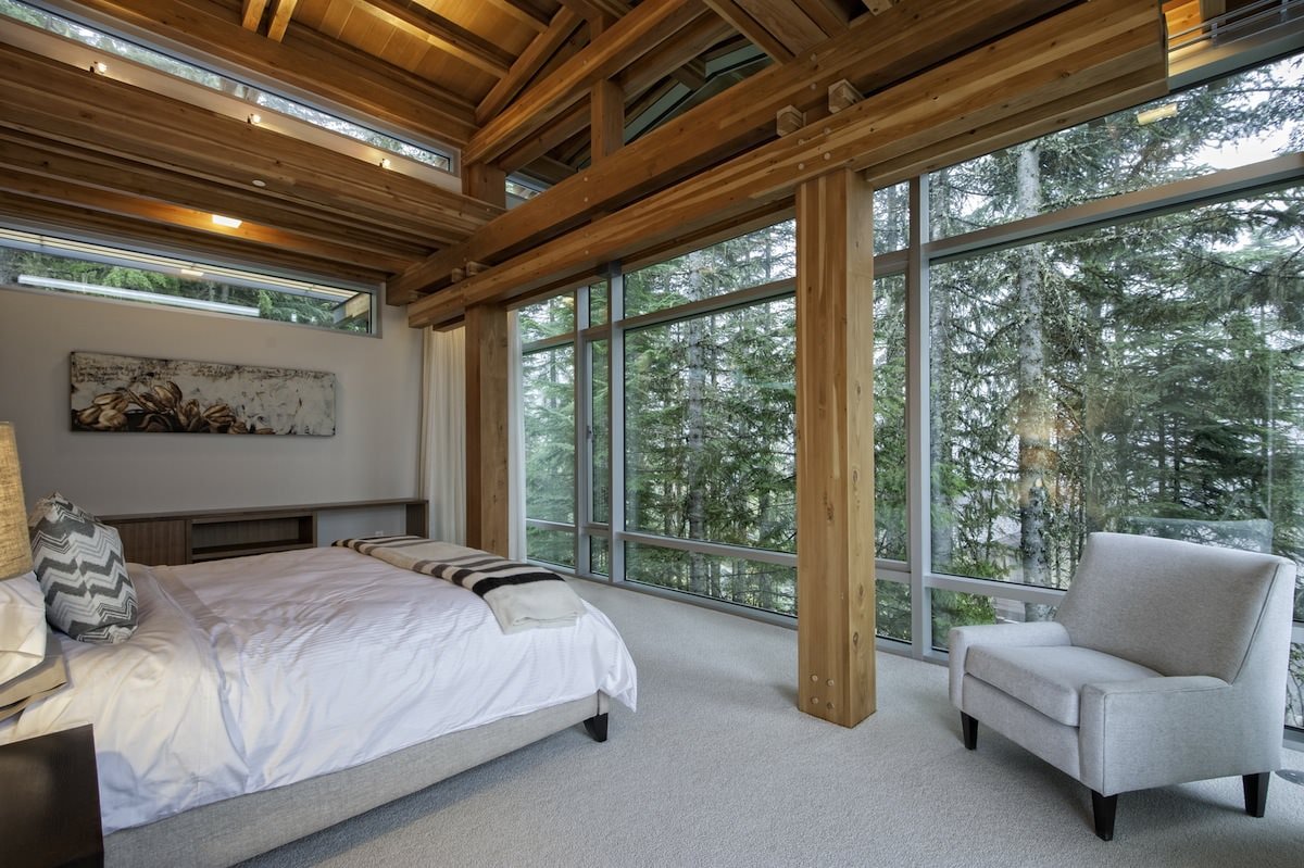 Interior de un dormitorio en una casa de campo con ventanas panorámicas
