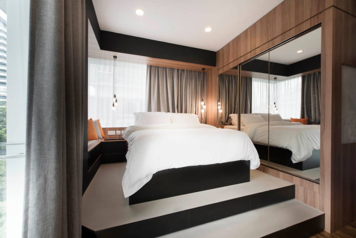Cama sobre plataforma elevada con espejo lateral