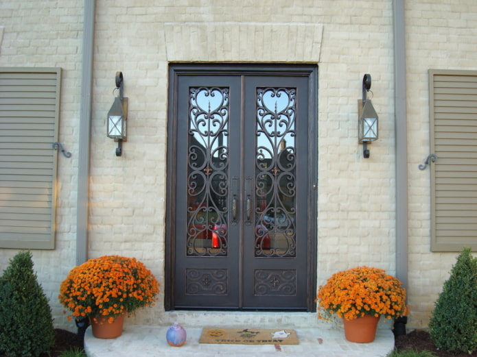 Porche de una casa de campo con puerta de entrada de forja y cristal