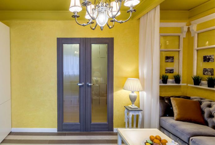combinación de paredes amarillas con una puerta marrón oscuro con inserciones de vidrio