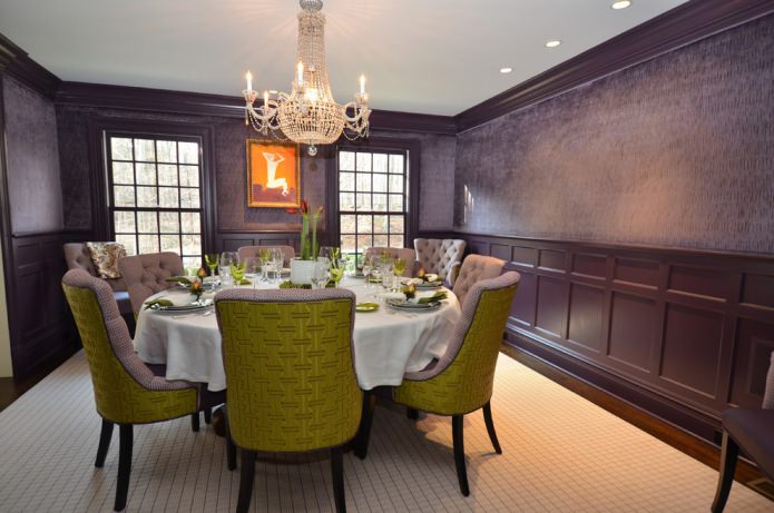 comedor con papel pintado morado oscuro y sillas verdes y lilas
