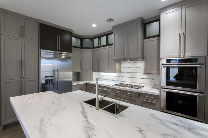 Cocina con muebles gris claro y encimeras de piedra blanca