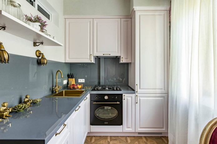 cocina pequeña con muebles blancos, encimeras grises y un delantal del mismo material