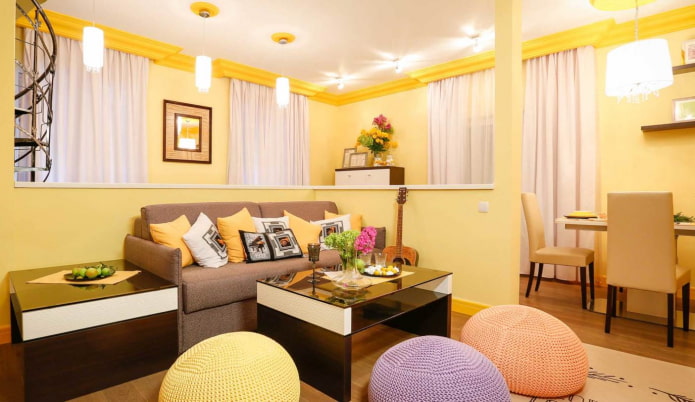 Sala de estar amarillo claro con cojines multicolores y pufs de punto